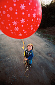 Child holding red balloon