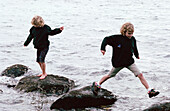 Two sisters run along a beach near Vancouver, British Columbia, Canada