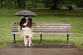 Woman on park bench, Public Garden, rain, Boston, Massachusetts. USA.