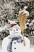 Snowman standing in a garden during snowfall.
