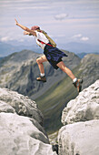 Female hiker leaping across rocks. New Zealand.
