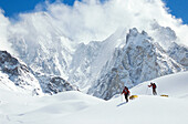 Skiers hauling sleds under Gasherbrum IV, Godwin-Austen glacier. Karakoram mountains, Pakistan
