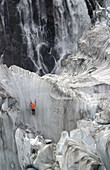 Climber on steep ice. Fox glacier crevasses near Victoria Falls. Westland National Park. South Island. New Zealand.