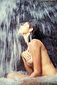 Nackte Frau unter einem Wasserfall