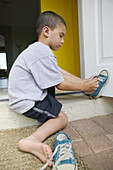 Boy putting on shoes outdoor
