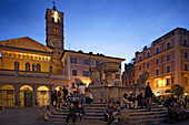 Menschen sitzen abends an einem Brunnen auf der Piazza Sta Maria, Trastevere, Rom, Italien, Europa