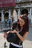 Frau füttert Tauben am Markusplatz, Venedig, Venetien, Italien, Europa