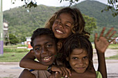 Portrait von drei lächelnden Aborigine Kindern in der Abenddämmerung, Palm Insel, Queensland, Australien