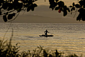 Mann wirft Speer im Kanu bei Sonnenuntergang, Neubritannien, Papua Neuguinea, Ozeanien