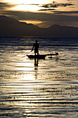 Man standing paddling in a canoo at sunset, New Britain, Papua New Guinea, Oceania