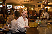 Friendly waitress serving apple cider in restaurant Zum Gemalten Haus in Sachsenhausen, Frankfurt, Hesse, Germany