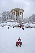 People sledging beneath the Monopteros temple at the English Garden, Munich, Bavaria, Germany