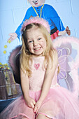 3 year old girl looking into camera, wearing a fairy outfit looking delighted and excited