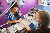 Woman having her nail done with a nail therapist in a salon