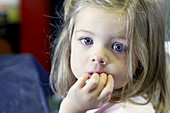 3 year old girl, looking into camera, at nursery, serious, hand in her mouth