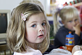 3 year old girl, looking into camera, at nursery, serious