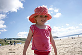 4 year old girl standing on the beach smiling into camera