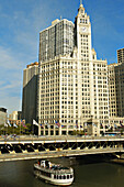 USA, Illinois, Chicago. Wrigley Building on Michigan Avenue, flags on bridge over Chicago River, tour boat