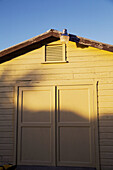 BELIZE Ambergris Caye Exterior of yellow wooden building in late afternoon, closed wooden doors