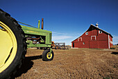 Red barn and green tractor. Western Nebraska. USA.