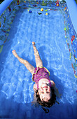 Girl (3yr) floating in an inflatable pool