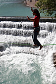 Young man balancing on rope over a river, Fussen, Bavaria, Germany