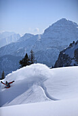 Snowboarder carving turns downhill, Reutte, Tyrol, Austria