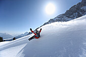 Snowboarder carving turns downhill, Reutte, Tyrol, Austria