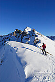 young woman ascending ridge with cornices of Engelspitze, Lechtal range, Tyrol, Austria