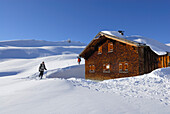 Skifahrer kommen bei verschneiter Almhütte an, Schwarzwassertal, Kleinwalsertal, Allgäuer Alpen, Allgäu, Vorarlberg, Österreich