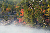 Misty shore of Simon Lake with early autumn colour. Naughton, Ontario, Canada 