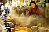 Woman selling food outside of restaurant in Namdaemon market. Seoul, South Korea.