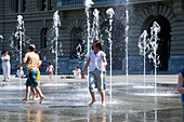 Children playing in the trick fountains and water gardens in front of the House of Parliament on Parliament Square, Bundeshaus, Bundesplatz, Old City of Berne, Berne, Switzerland