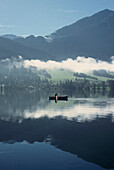 Reflection of a boat and mountains on Tegernsee lake, Bavaria, Germany