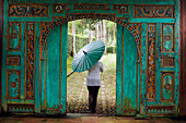 Woman walking through a traditional, nicely carved door at Losari Coffee Plantation in West Java, Indonesia, South East Asia
