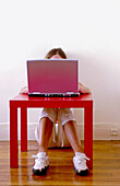 Young woman sitting on floor with computer and red desk. Paris. France
