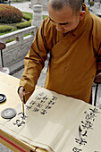 Monk writing in a decorative hand at great wild goose pagoda or Dayanta. Xi an city. Shaanxi province. China.
