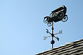 Weather vane in the shape of an antique automobile car shows the direction of the wind