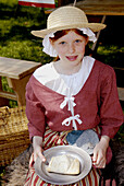 Girl in costume eating pieCirca 1700 reenactment of the Colonial period lifestyle in Southeastern Michigan at the Feaste of Sainte Claire Port Huron Michigan
