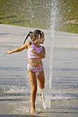 Child playing at a public water park on a hot summer day