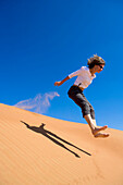 Woman jumping on dune, Arabian Desert, United Arab Emirates
