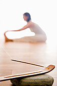 Mid adult woman practising yoga, joss stick in foreground, yoga studio at Linz, Austria