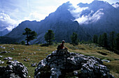 Hiker, woman sitting on rocks admiring the mountain landscape, Triglav National Park near Vrsic Pass, Slovenia