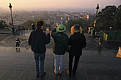 Drei Personen mit Biergläsern blicken über die Stadt im Morgenlicht, Paris, Frankreich, Europa