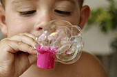 Two year old boy blowing bubbles
