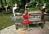 Two young buddhist monks and Buddha images. Bago. Myanmar (Burma).