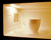 One white coffee mug inside a microwave