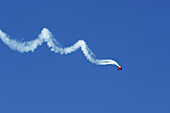 Stunt plane spiraling across the deep blue sky in an air show