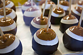Row of chocolate marshmallow caramel apples drying on a sheet at an amusement park.