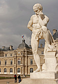 Statue of a man with the French Senate Building in the background. Luxembourg Gardens. Paris, France